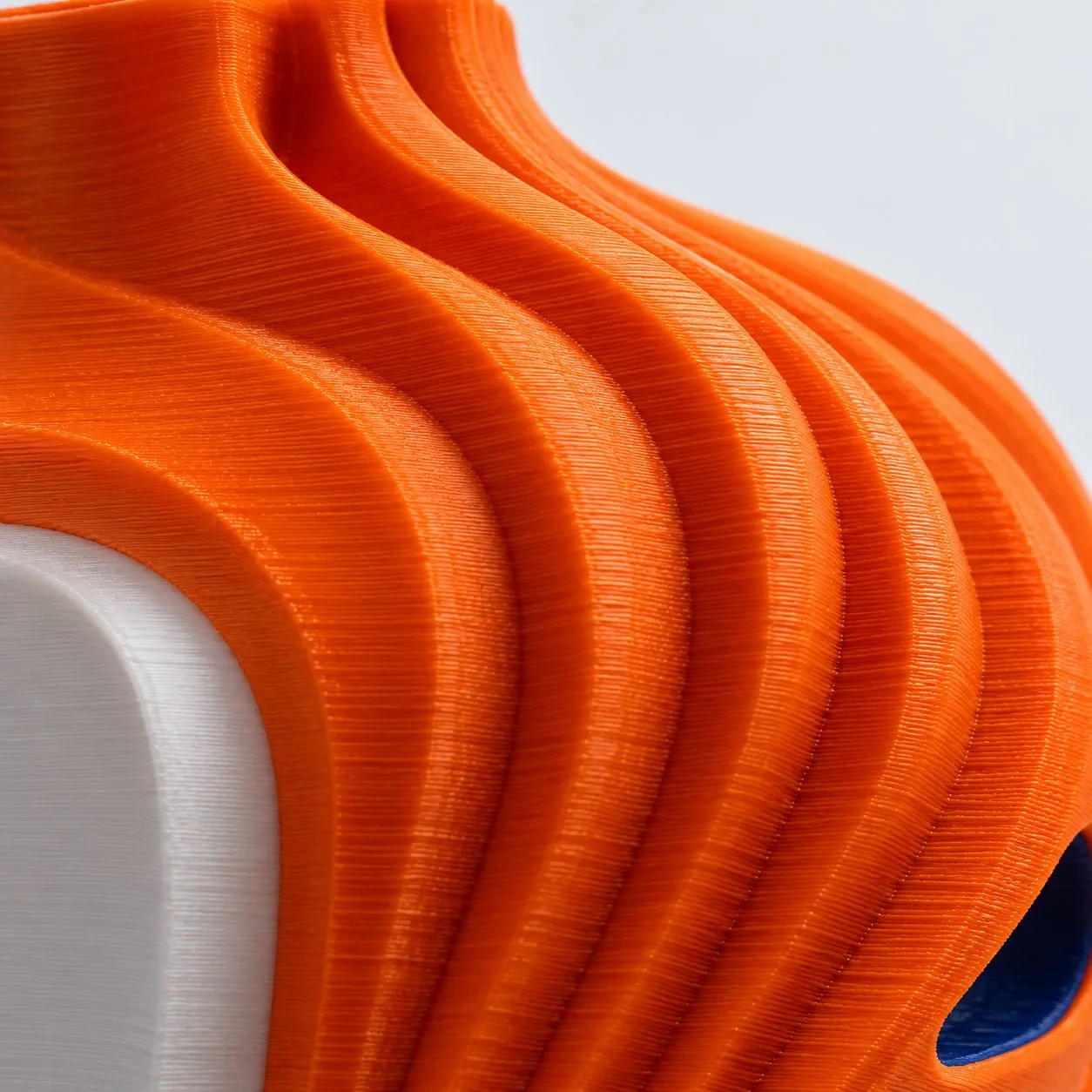 Detalhe das camadas de uma peça laranja impressa em 3D